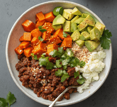 Meal prep containers filled with High Protein Beef & Sweet Potato Bowl ingredients including avocado and cottage cheese